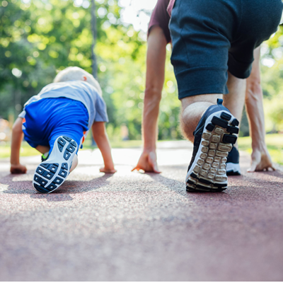 Father and son crouch in runner's stance ready to race each other down an empty suburban street Father and son crouch in runner's stance ready to race each other down an empty suburban street