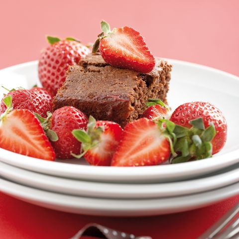 Luscious chocolate cake loaded with fresh strawberries on a white dessert plate Luscious chocolate cake loaded with fresh strawberries on a white dessert plate