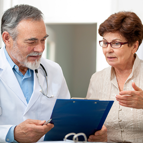 Elderly physician holding clipboard and discussing results with patient Elderly physician holding clipboard and discussing results with patient