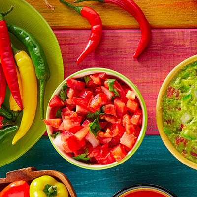 Colorful table loaded with bowls of diced tomatoes, guacamole, and assorted peppers Colorful table loaded with bowls of diced tomatoes, guacamole, and assorted peppers