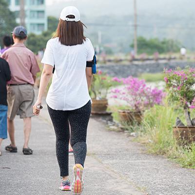Woman in workout gear walking alongside urban flower patch